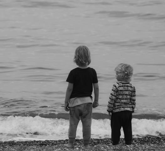 two children standing on the beach shore